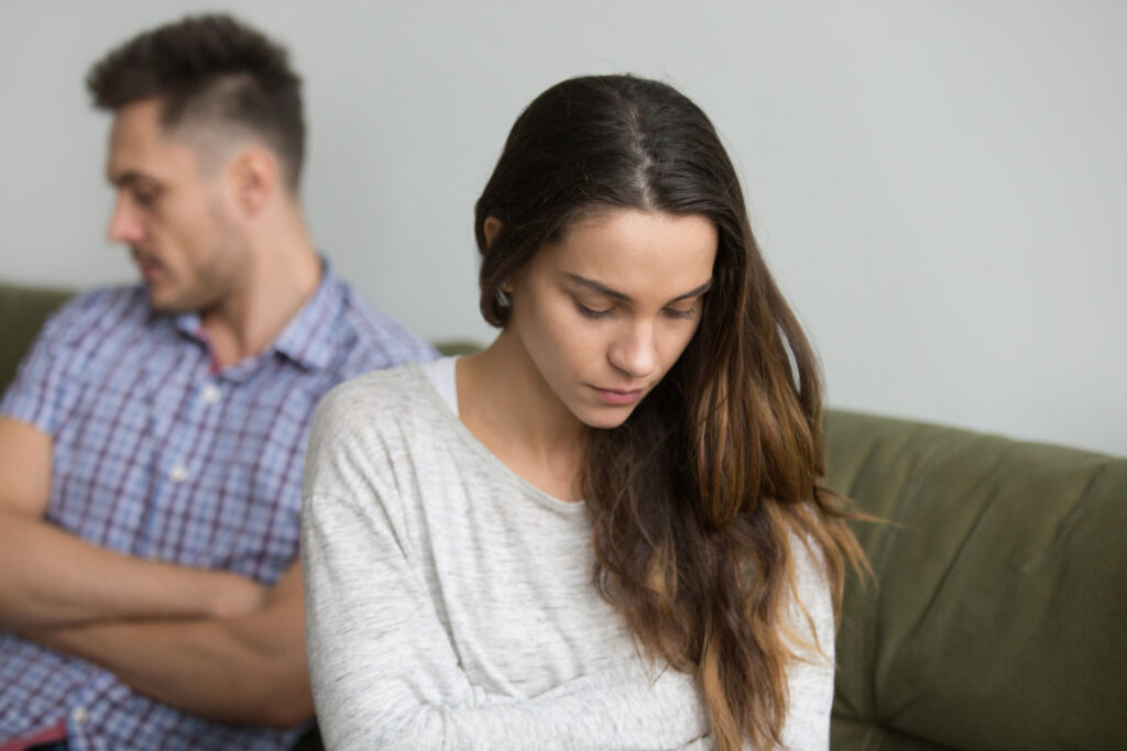 Casal sentado em silêncio na sala, simbolizando o distanciamento emocional.